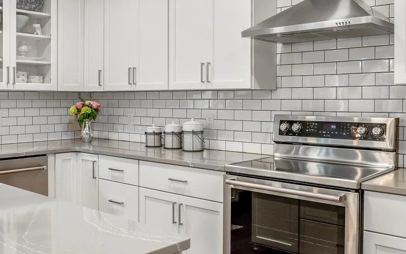 A modern kitchen featuring stainless steel appliances and sleek white cabinets.