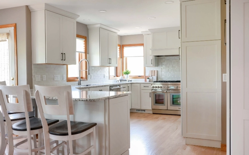 A modern kitchen featuring white cabinets and warm wooden floors, creating a bright and inviting atmosphere.