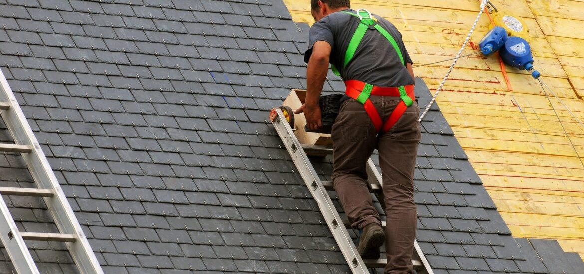 A man on a ladder performing roofing work on a house, showcasing professional roofing services in action