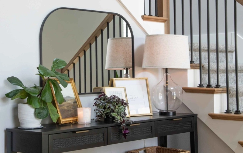 A black console table featuring a mirror and a lamp, elegantly arranged for a stylish entryway or living space.
