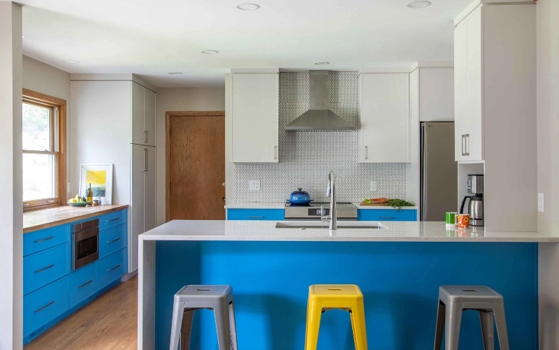 A vibrant blue kitchen with cheerful yellow stools positioned at the counter.