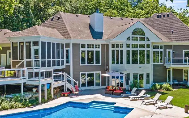 A large home featuring a swimming pool and a spacious deck for outdoor relaxation and entertainment.