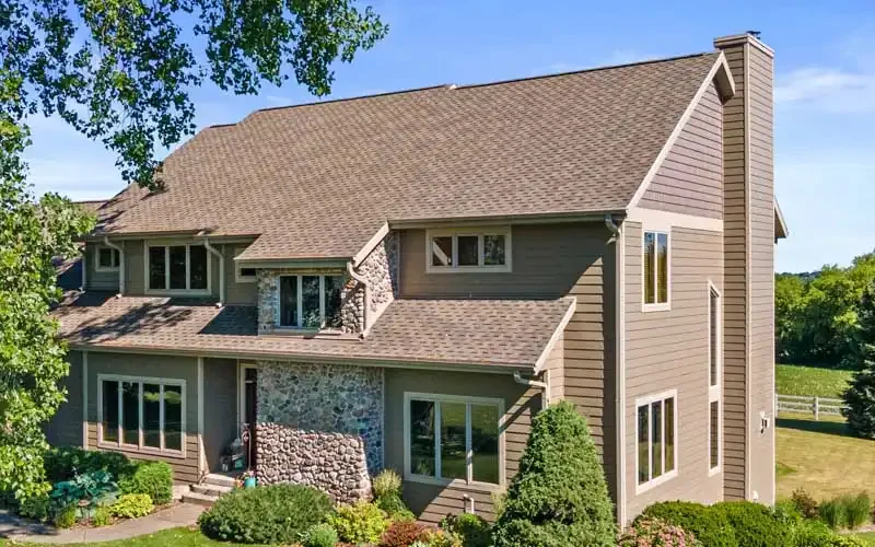 A sizable house with a vast yard and a wide driveway in front.