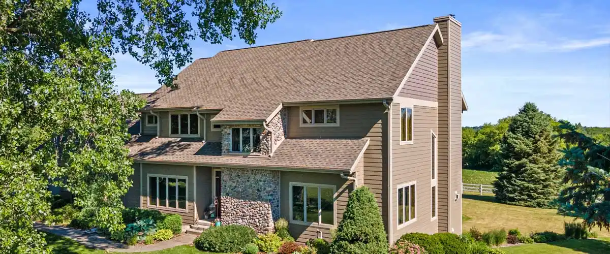 A sizable house with a vast yard and a wide driveway in front.