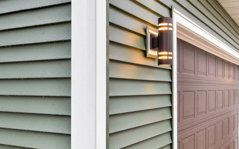 A garage door illuminated by a light, showcasing its structure and the surrounding area.