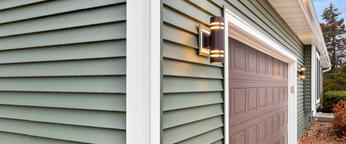 A garage door illuminated by a light, showcasing its structure and the surrounding area.