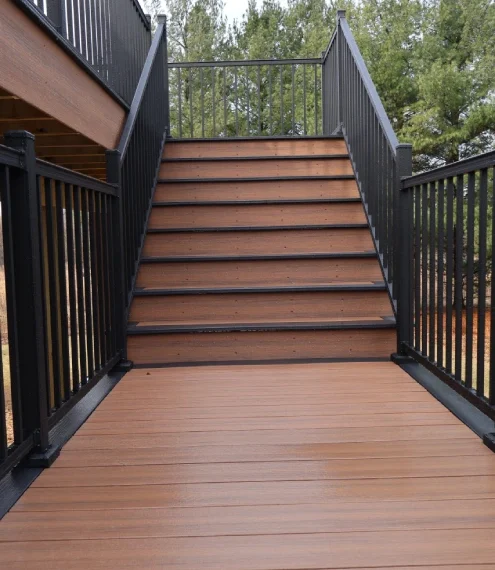 A wooden deck featuring a black railing and stairs, providing a stylish outdoor space for relaxation.